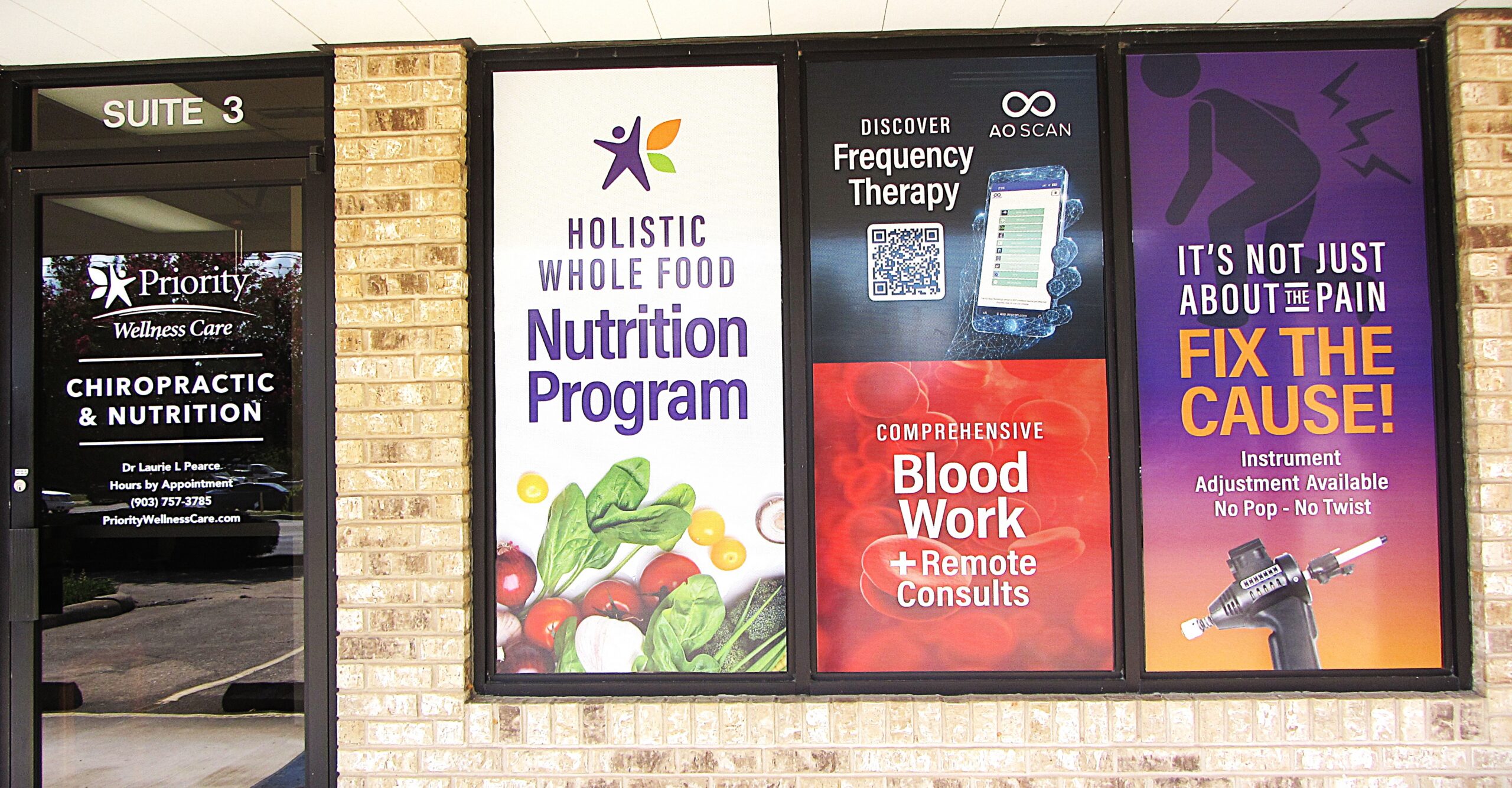 Priority Wellness Care storefront in Longview, Texas &mdash; Suite 3 window signage for holistic whole food nutrition, comprehensive blood work with remote consults, AO Scan frequency therapy, and chiropractic instrument adjustment.